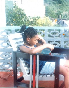 Jasmine Richards as a child, sat outside reading