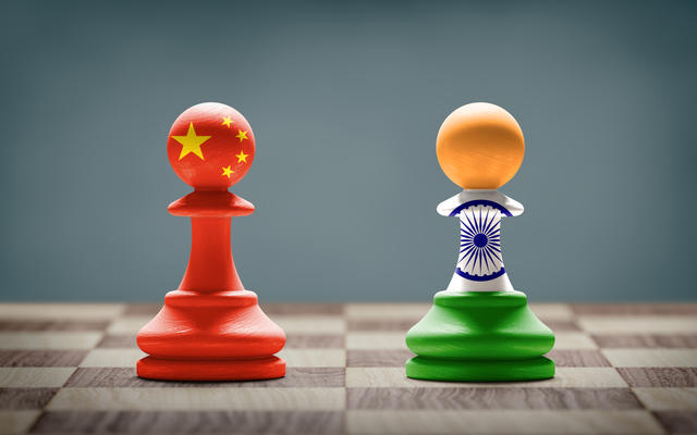 Two chess pawns - one is painted in the colours of the flag of the China, the other in the colours of the flag of India