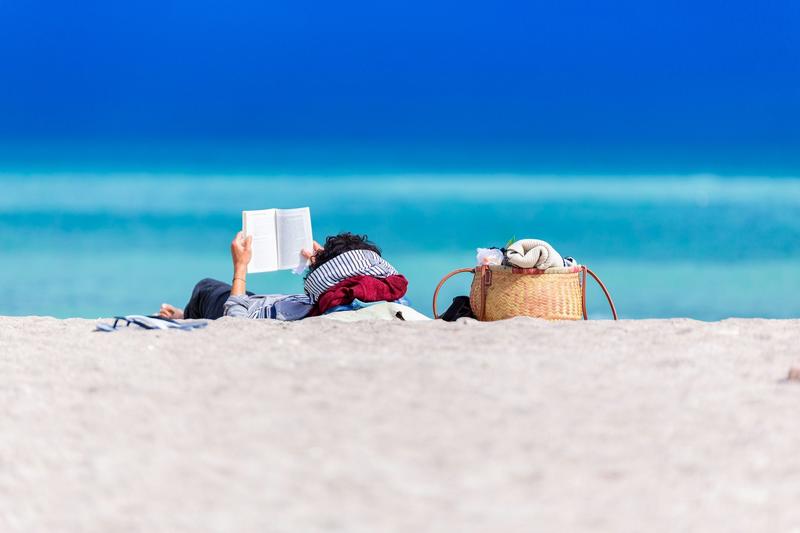 Person reading a book on a beach