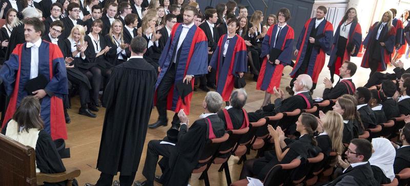 Students walking in a line to receive their graduation certificates