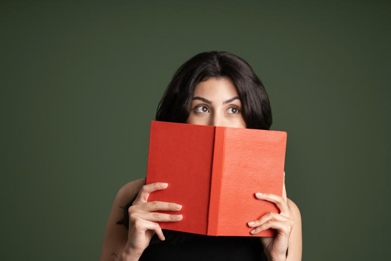 Young woman holding book to her face