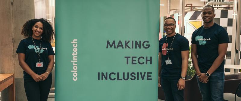 Three members of the colorintech team stood next to a banner which reads 'colorintech' and 'Making tech inclusive'