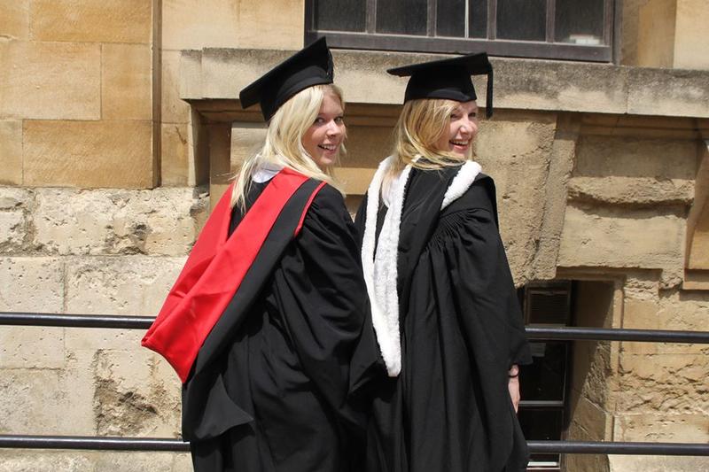 Emma Yandle with a friend, both in graduation gowns and caps, walking through Oxford