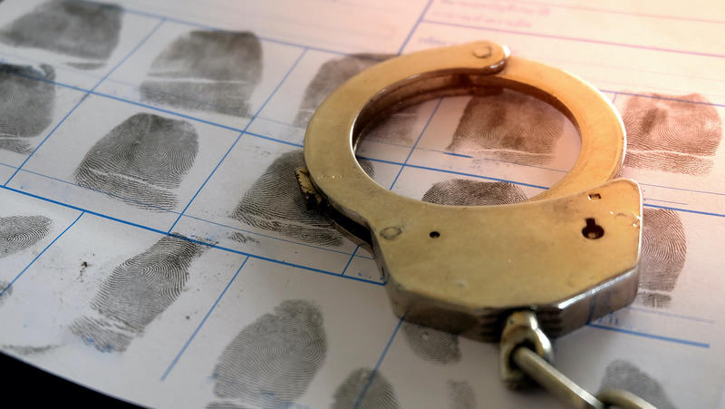 Handcuff portrayed against a sheet of fingerprints