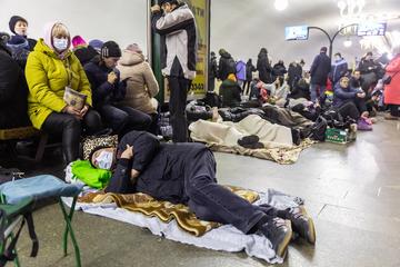 Displaced Ukrainians wait in a travel terminus, some asleep
